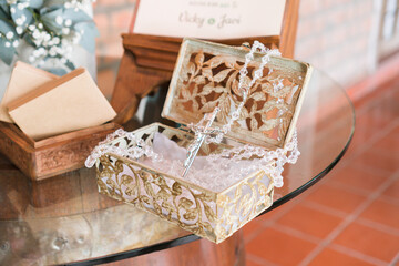 Close-up of small golden box with crucifix and necklace inside. Wedding details. Religion.