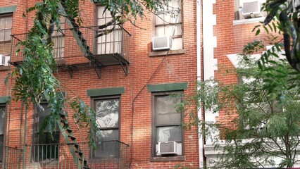 Naklejka premium New York City classic building architecture, Manhattan, USA. Urban residential house exterior. Real estate property in United States. Typical red brick facade. Fire escape, emergency ladder exit.