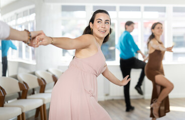 Couples in evening dresses suits enjoys pair dance boogie-woogie, positively interacting with each other on floor. Dance party , hobby for lovers of active lifestyle