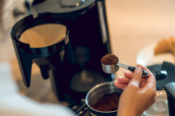 Close up of womans hand with a full spoon of coffee