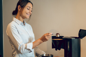 Dark-haired young woman in the kitchen making coffee in the coffee machine