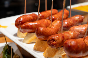 Typical snacks of Basque Country, pinchos or pinxtos skewers with small pieces of bread, fish, sea food, sweet green pepper served in bar in San-Sebastian or Bilbao, Spain