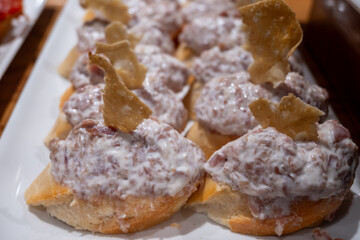 Typical snacks of Basque Country, pinchos or pinxtos skewers with small pieces of bread, fish, sea food, sweet green pepper served in bar in San-Sebastian or Bilbao, Spain