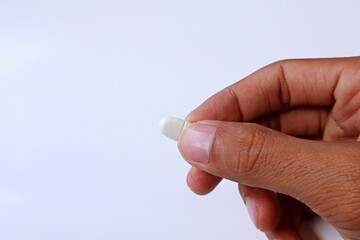 Man hand taking white medicine pill on white background