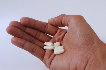 Man holding white medicine pill on white background