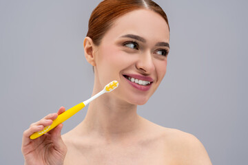 Beautiful young red-haired woman brushing her teeth with toothbrush