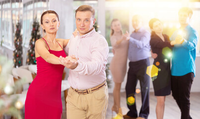 Men and women dancing tango or samba next to the Christmas tree