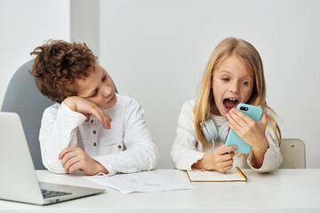 Smiling siblings playing and blogging together on their smart phones in the comfort of their home Happy and connected, these two teenagers capture the essence of sibling friendship and online