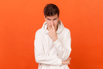 You lie. Portrait of young man wearing white hoodie looking at camera and pointing at his nose,...