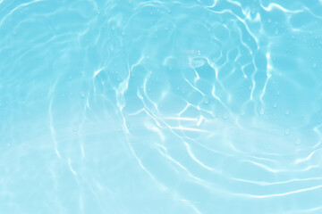 Blue water with ripples on the surface. Defocus blurred transparent blue colored clear calm water surface texture with splashes and bubbles. Water waves with shining pattern texture background.