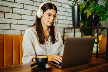 Young caucasian woman working or studying on laptop from cafe 