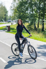 Naklejka premium Caucasian woman riding a bike in a park. Vertical photo. 