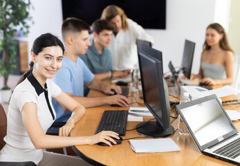 Obraz premium Positive young girl, student of computer academy, was distracted during class and dreamily looks away