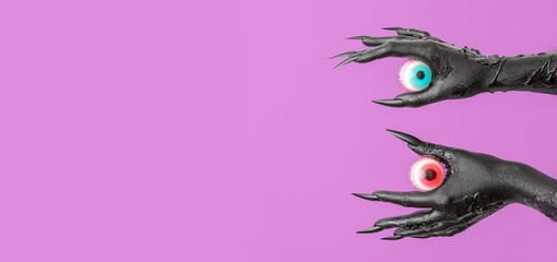 Black hands of monster holding eyeballs on purple background with space for text. Halloween...