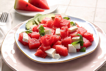 Plate of tasty watermelon salad on white tile background