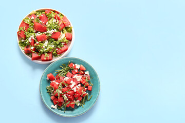 Plates of tasty watermelon salad on blue background