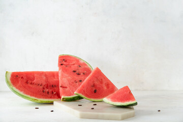 Board with pieces of ripe fresh watermelon on light background