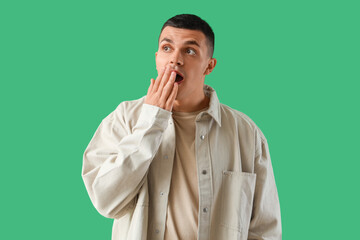 Shocked young man on green background