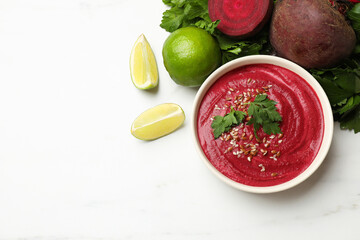 Tasty beetroot hummus in bowl and products on white marble table, flat lay. Space for text