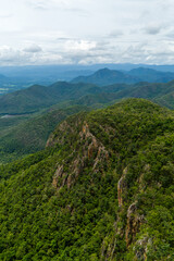Stunning aerial view of dense green mountains and valleys with a cloudy sky in the background,...