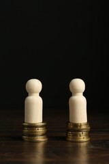Financial equality. Wooden figures with similar quantity of coins on table