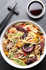 Stir-fry noodles with sea food served on grey textured table, flat lay
