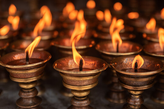 Burning butter lamp close-up. Butter lamps, traditionally burning yak butter, are used in Tibetan Buddhist monasteries for meditation and rituals, symbolizing enlightenment and dispelling darkness.