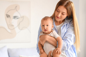 Beautiful young happy mother with cute little baby in bedroom at home