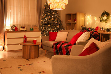 Interior of cozy living room with sofa and Christmas tree decorated for holiday at night