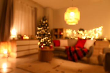 Interior of cozy living room with sofa and Christmas tree decorated for holiday at night, blurred view