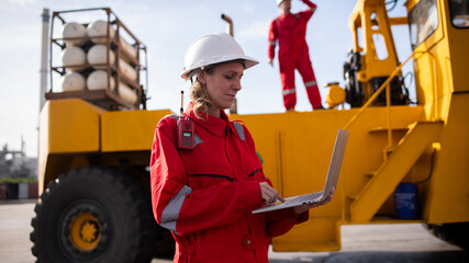 Engineer or worker are standing forklift or truck vehicle are holding detail and appear to be discussing or reviewing documents, likely related to inspect about factory and industry environment.