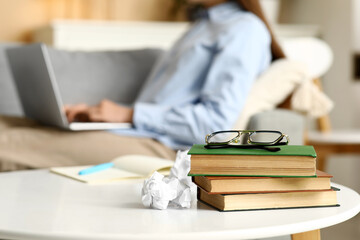 Beautiful female writer with laptop, notebook and books on  table, closeup