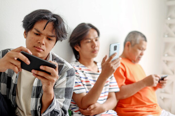 Modern Asian Father And His Two Son Using Mobile Phone Playing Games Together
