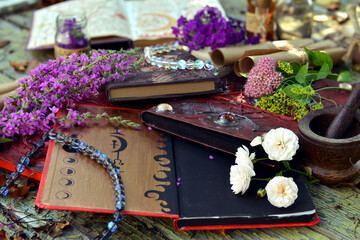 Mystic still life with magic book of spells, flowers and witchy ritual objects on old table. Occult, esoteric, wicca and divination concept. No foreign language, all symbols are fictional