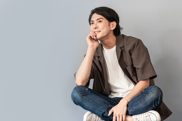 椅子に座るスニーカーとジーンズ姿のさわやかな男性
