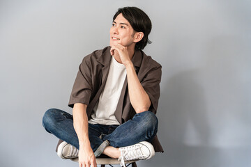 椅子に座るスニーカーとジーンズ姿のさわやかな男性
