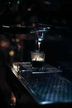 Close-up of espresso pouring from coffee machine. Professional coffee brewing.