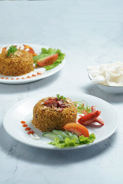 Two Plates of Nasi Goreng With Rice, Vegetables, and Sausage on Marble Table