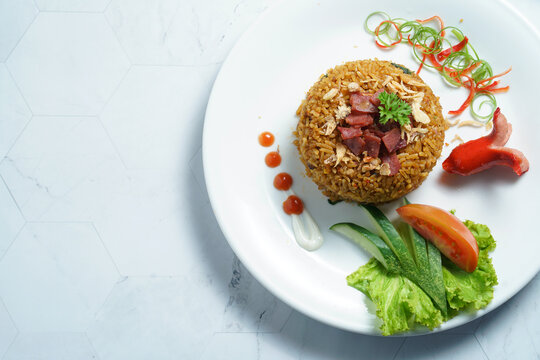 A Plate of Nasi Goreng With Rice, Vegetables, and Sausage on Marble Table