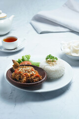 Ayam geprek is a typical Indonesian dish of fried chicken with flour that is mashed or mashed with plow chili sauce.