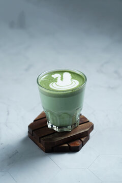 Cup of Matcha Latte With Latte Art on White Marble Table