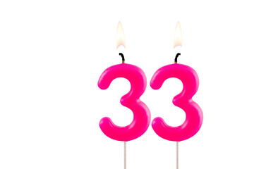 Pink number 33 birthday candle lit on white background