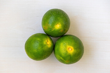 Fresh green malta fruits on a light wooden surface. It is a citrus fruit, also known as sweet orange and mosambi. Top view.