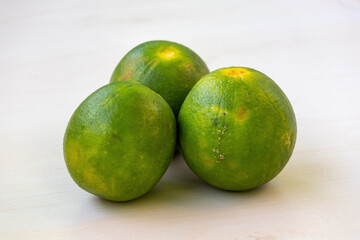 Fresh green malta fruits on a light wooden background. It is a citrus fruit, also known as sweet...