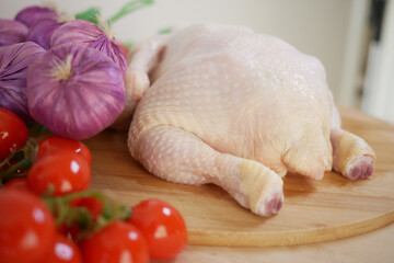 A delicious plate of Fresh Chicken accompanied by Vegetables placed on a Wooden Cutting Board