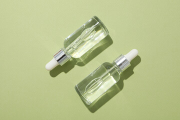 Transparent cosmetic bottles on a green background
