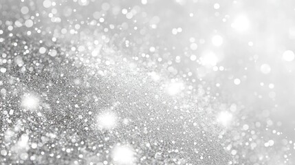 Close-up of shiny silver glitter particles against a white background, creating a sparkling effect.