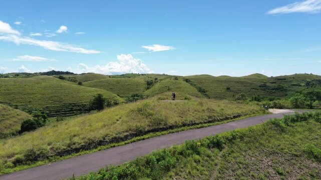 Rolling green hills of Teletubbies Hill under a clear blue sky in Indonesia