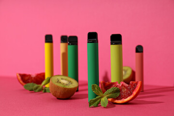 Electronic cigarettes with fresh kiwi on a pink background