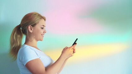 Typing message. Smartphone chat. Cheerful vivid woman smiling enjoying social media texting online blur rainbow color gradient empty space background.